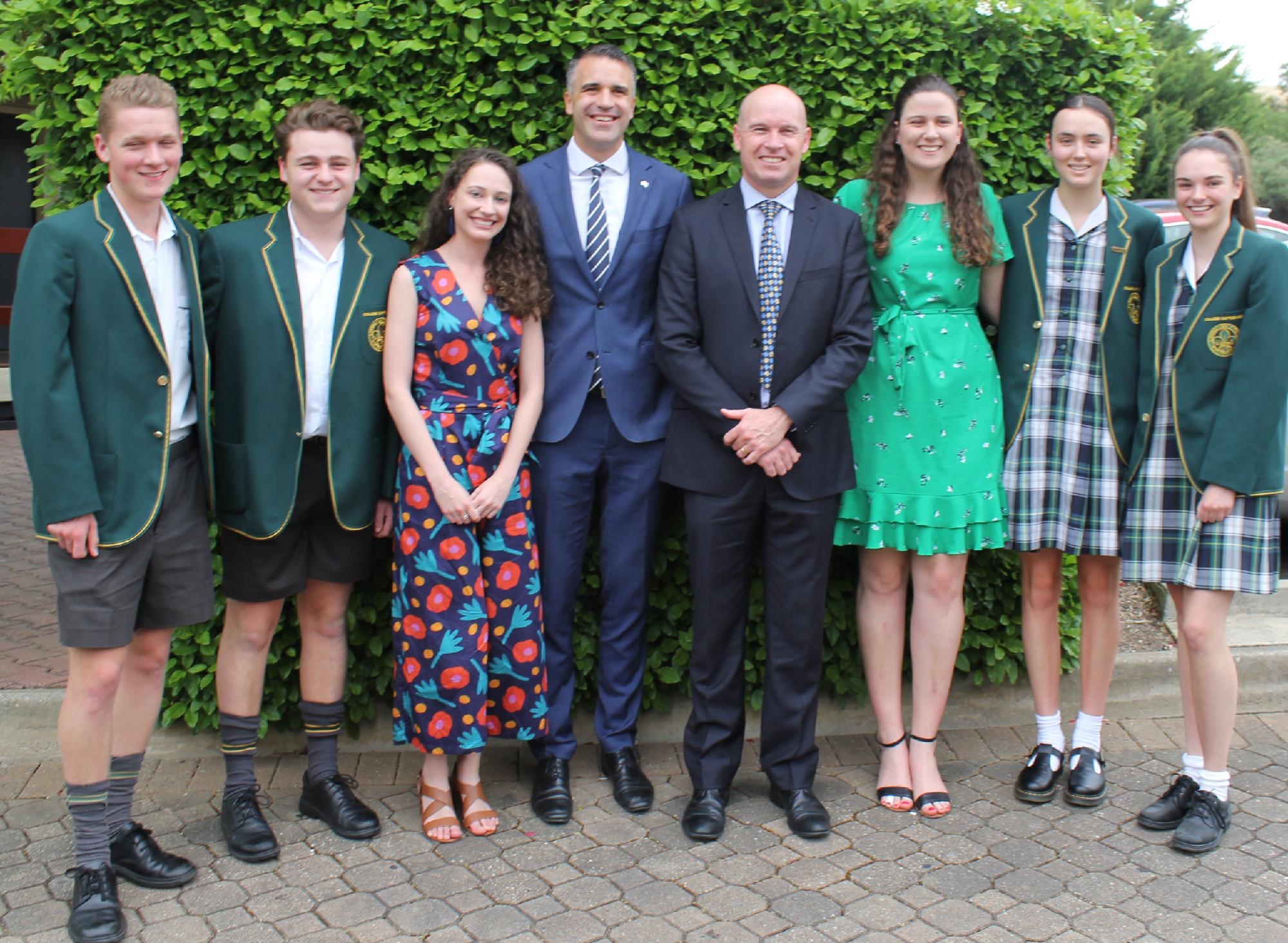 Mercedes College student leaders and staff posing together outdoors in front of greenery.